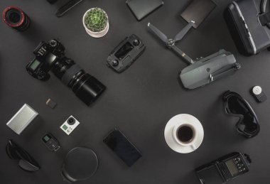 Çalışma alanı fotoğrafçı ile dizüstü bilgisayar, dijital kamera, bellek kartı, kamera, dron, uzaktan kumanda, telefon, Vr gözlük ve Fotoğrafçılık. Üstten görünüm siyah tablo arka plan üzerinde. Mockup şablon kavramı.