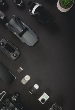 Çalışma alanı fotoğrafçı ile dizüstü bilgisayar, dijital kamera, bellek kartı, kamera, dron, uzaktan kumanda, telefon, Vr gözlük ve Fotoğrafçılık. Üstten görünüm siyah tablo arka plan üzerinde. Mockup şablon kavramı.