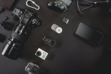Çalışma alanı fotoğrafçı ile dizüstü bilgisayar, dijital kamera, bellek kartı, kamera, dron, uzaktan kumanda, telefon, Vr gözlük ve Fotoğrafçılık. Üstten görünüm siyah tablo arka plan üzerinde. Mockup şablon kavramı.