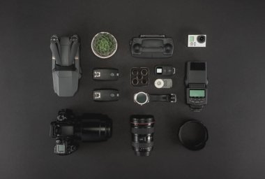 Çalışma alanı fotoğrafçı ile dizüstü bilgisayar, dijital kamera, bellek kartı, kamera, dron, uzaktan kumanda, telefon, Vr gözlük ve Fotoğrafçılık. Üstten görünüm siyah tablo arka plan üzerinde. Mockup şablon kavramı.