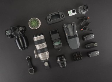 Çalışma alanı fotoğrafçı ile dizüstü bilgisayar, dijital kamera, bellek kartı, kamera, dron, uzaktan kumanda, telefon, Vr gözlük ve Fotoğrafçılık. Üstten görünüm siyah tablo arka plan üzerinde. Mockup şablon kavramı.