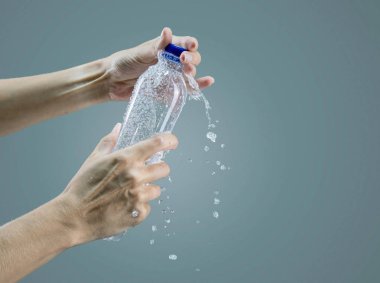 Bir şişe köpüklü su sıçramalarına ve gri arka plan üzerinde damla sürü ile açılış kadın eli. Studio fotoğraf çekim. Sağlık yaşam kavramı