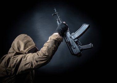 Maske ve koyu arka plan makinalı tüfek ile tehlikeli silahlı terör. Terör ve şiddet kavramı.