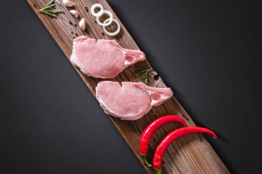 Delicious raw pork steak with peppers and onions. Meat and rosemary on wooden background. clipart