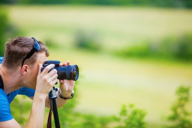 Profesyonel fotoğrafçı dağlar ve yamaçlar arka planı vizör bakarak kamera ayarlarını denetler