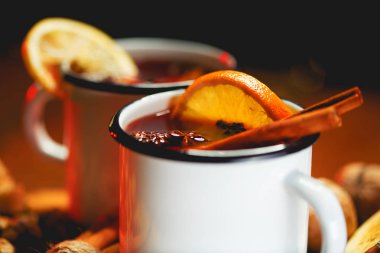 Baharatlar ve narenciye meyve ahşap yüzey üzerinde beyaz rustik kupalar sıcak mulled şarap. Hamur metin için yer.