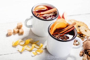 Baharatlar ve narenciye meyve ahşap yüzey üzerinde beyaz rustik kupalar sıcak mulled şarap. Hamur metin için yer.