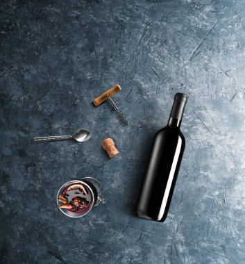 Mulled şarap tarifi Malzemeler ve mutfak aksesuarları, bir şişe kırmızı şarap, tarçın, Anason yıldız, turuncu, kahverengi bardaksoğuk baharat mavi taş zemin üzerine.