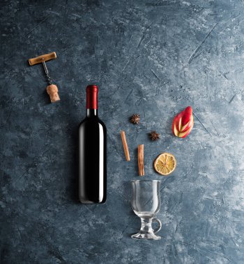 Mulled şarap tarifi Malzemeler ve mutfak aksesuarları, bir şişe kırmızı şarap, tarçın, Anason yıldız, turuncu, kahverengi bardaksoğuk baharat mavi taş zemin üzerine.