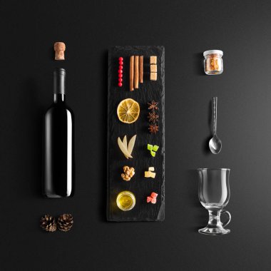 Mulled şarap tarifi Malzemeler ve mutfak aksesuarları, bir şişe kırmızı şarap, tarçın, Anason yıldız, turuncu, kahverengi bardaksoğuk baharat siyah arka plan üzerine.