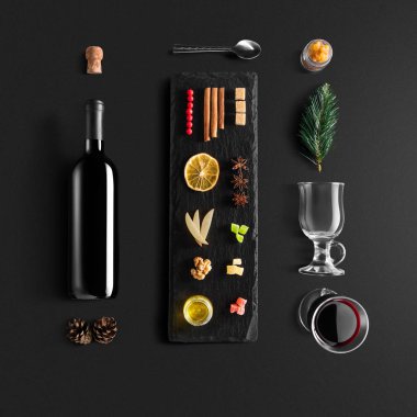 Mulled şarap tarifi Malzemeler ve mutfak aksesuarları, bir şişe kırmızı şarap, tarçın, Anason yıldız, turuncu, kahverengi bardaksoğuk baharat siyah arka plan üzerine.