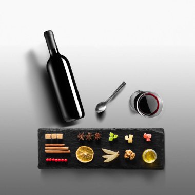 Mulled şarap tarifi Malzemeler ve mutfak aksesuarları, bir şişe kırmızı şarap, tarçın, Anason yıldız, turuncu, kahverengi bardaksoğuk baharat gri arka plan üzerinde.