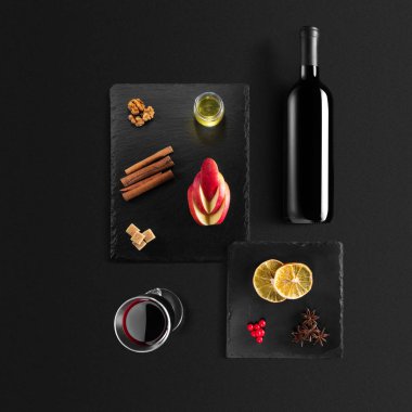 Mulled şarap tarifi Malzemeler ve mutfak aksesuarları, bir şişe kırmızı şarap, tarçın, Anason yıldız, turuncu, kahverengi bardaksoğuk baharat siyah arka plan üzerine.