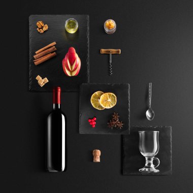 Mulled şarap tarifi Malzemeler ve mutfak aksesuarları, bir şişe kırmızı şarap, tarçın, Anason yıldız, turuncu, kahverengi bardaksoğuk baharat siyah arka plan üzerine.