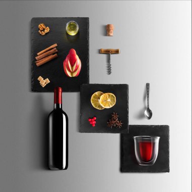 Mulled şarap tarifi Malzemeler ve mutfak aksesuarları, bir şişe kırmızı şarap, tarçın, Anason yıldız, turuncu, kahverengi bardaksoğuk baharat gri arka plan üzerinde.