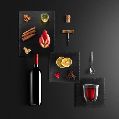 Mulled şarap tarifi Malzemeler ve mutfak aksesuarları, bir şişe kırmızı şarap, tarçın, Anason yıldız, turuncu, kahverengi bardaksoğuk baharat siyah arka plan üzerine.