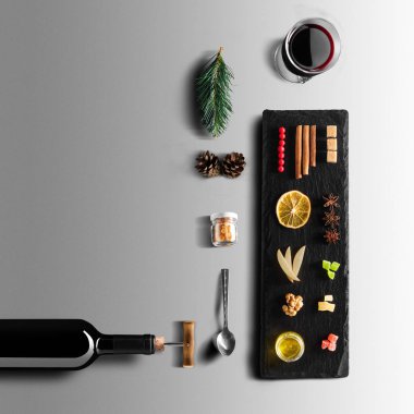 Mulled şarap tarifi Malzemeler ve mutfak aksesuarları, bir şişe kırmızı şarap, tarçın, Anason yıldız, turuncu, kahverengi bardaksoğuk baharat gri arka plan üzerinde.