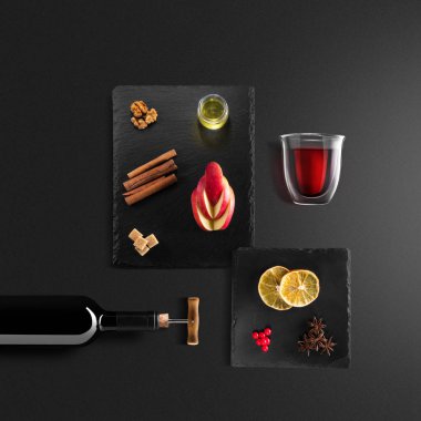 Mulled şarap tarifi Malzemeler ve mutfak aksesuarları, bir şişe kırmızı şarap, tarçın, Anason yıldız, turuncu, kahverengi bardaksoğuk baharat siyah arka plan üzerine.