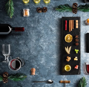 Mulled şarap tarifi Malzemeler ve mutfak aksesuarları, bir şişe kırmızı şarap, tarçın, Anason yıldız, turuncu, kahverengi bardaksoğuk baharat mavi taş zemin üzerine.