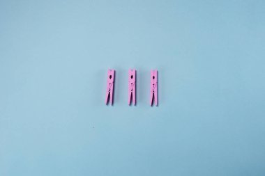 Pembe closespins pastel mavi arka plan üzerinde yatıyor. Minimal yaz co
