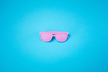 Pastel mavi arka plan üzerinde pembe cam yatıyor. Minimal yaz konsepti