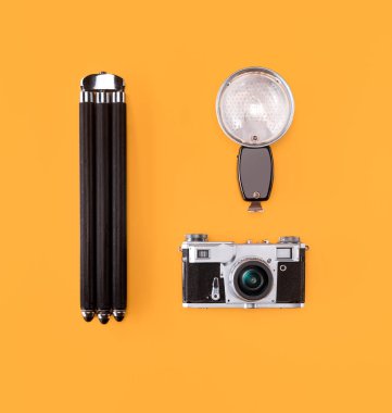 Turuncu arka plan üzerinde eski vintage retro kamera, flaş ve tripod ile düz yatıyordu