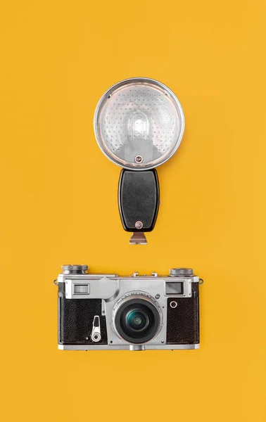 Piso con la vieja cámara retro vintage, flash y trípode sobre fondo naranja — Foto de Stock