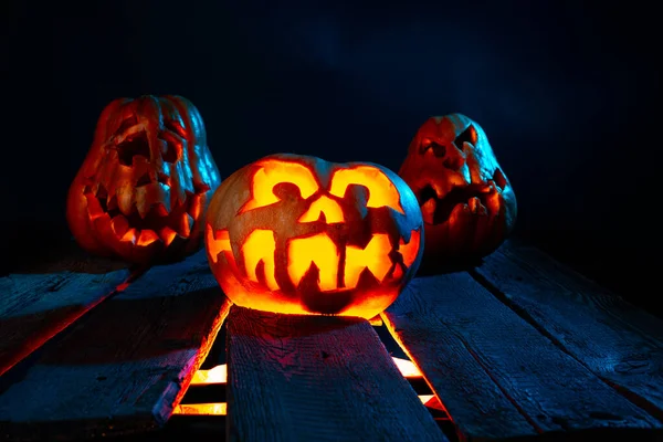 Calabazas de Halloween aterradoras en madera en un lugar espeluznante por la noche. Concepto de cartel —  Fotos de Stock