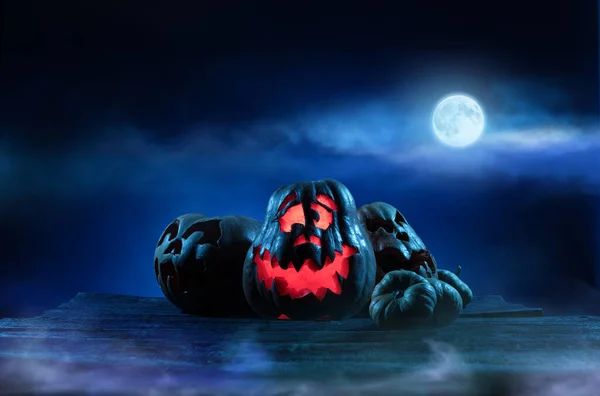 Calabazas de Halloween aterradoras en madera en un lugar espeluznante por la noche. Concepto de cartel — Foto de Stock