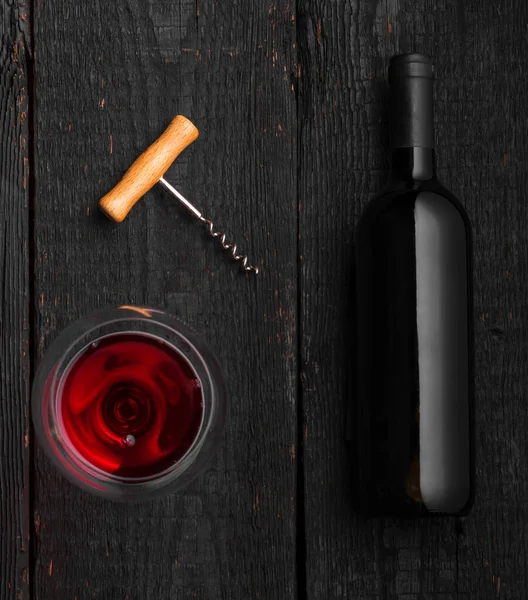 Μαύρο γυάλινο μπουκάλι με κρασί με φελλούς σε μαύρο ξύλινο φόντο — Φωτογραφία Αρχείου