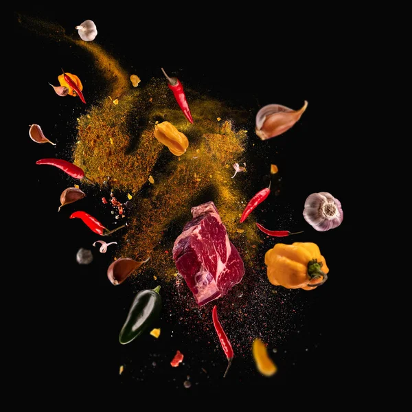 Hot red pepper, garlic, different spices powder meat stakes flying on a black background Motion freeze photo composition — Stock Photo, Image