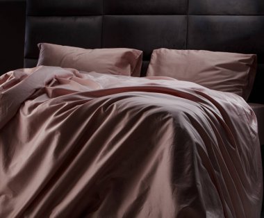 A beautifully arranged soft pink bedding is draped over a modern bed in a stylish bedroom. The fabric creates a warm and inviting ambiance that enhances the decor.
