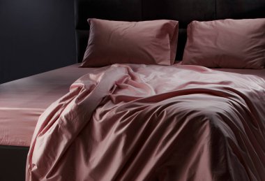A beautifully arranged soft pink bedding is draped over a modern bed in a stylish bedroom. The fabric creates a warm and inviting ambiance that enhances the decor.