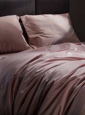 Luxurious pale pink bedding adorns a contemporary bed, featuring smooth pillows and sheets that create a cozy and inviting atmosphere in a stylish bedroom.