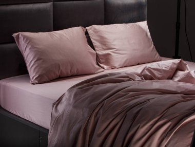 Luxurious pale pink bedding adorns a contemporary bed, featuring smooth pillows and sheets that create a cozy and inviting atmosphere in a stylish bedroom.