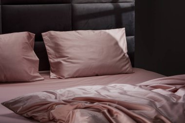 Luxurious pale pink bedding adorns a contemporary bed, featuring smooth pillows and sheets that create a cozy and inviting atmosphere in a stylish bedroom.