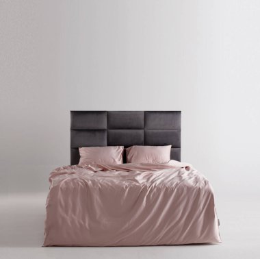 A chic bedroom showcases a sleek bed with a modern gray headboard. The soft pink bedding adds warmth, creating a cozy and inviting atmosphere in a minimalist setting.