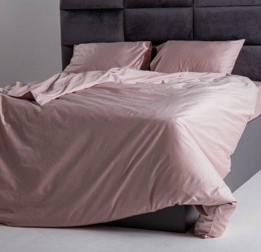 A sleek black bed frame complements soft pink sheets and pillows, creating a tranquil atmosphere in a minimally decorated bedroom space. Soft lighting enhances the peaceful environment.