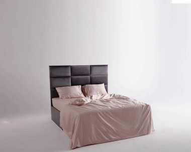 A sleek black bed frame complements soft pink sheets and pillows, creating a tranquil atmosphere in a minimally decorated bedroom space. Soft lighting enhances the peaceful environment.