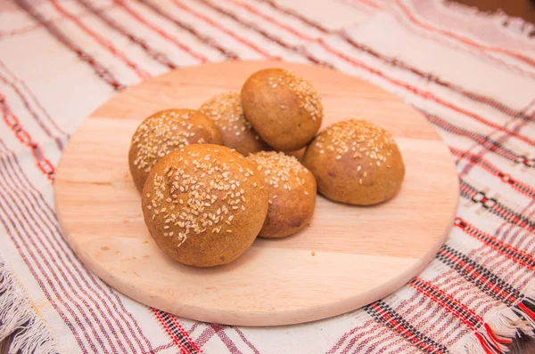 Smakelijke broodjes met sesam, op houten achtergrond — Stockfoto