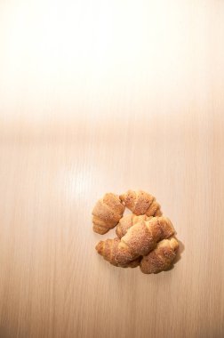 hafif ahşap bir masada taze pişmiş kruvasan