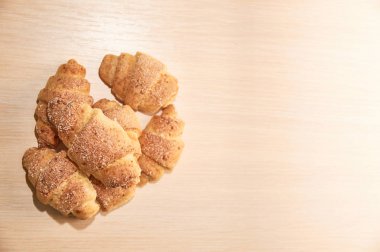 hafif ahşap bir masada taze pişmiş kruvasan