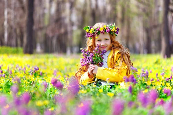 Little girl wearing flower headband collecting flowers in the forest