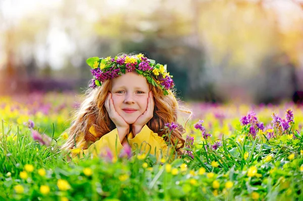 smiling girl wearing flower headband laying the grass