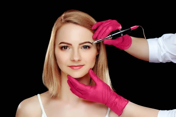 Beauty specialist correcting eyebrows against black background