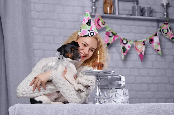 Woman with dog looking at birthday cake with burning candle