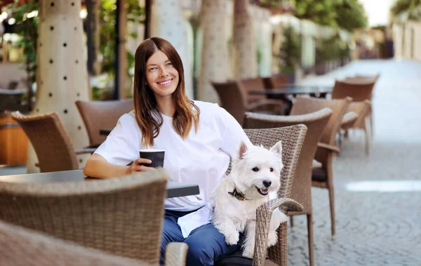 Happy woman at the street restaurant with her dog