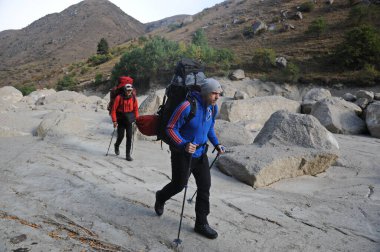 Almaty / Kazakistan - 09.15.2014: Özel ekipmanlı tırmanışçılar dağlara tırmanıyor. Dağlık bir nehirle kayalık bir geçitten geçmek.