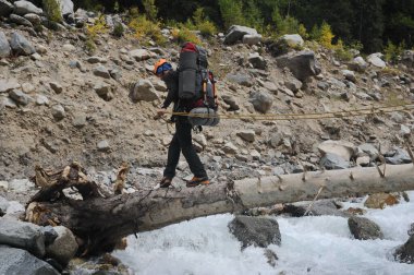 Almaty / Kazakistan - 09.15.2014: Özel ekipmanlı tırmanışçılar dağlara tırmanıyor. Dağlık bir nehirle kayalık bir geçitten geçmek.