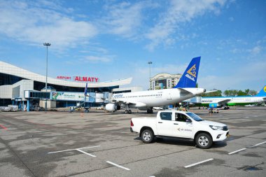 Almaty / Kazakistan - 04.23.2019: Bir uçak ve bir binanın arka planında havaalanı güvenlik aracı.
